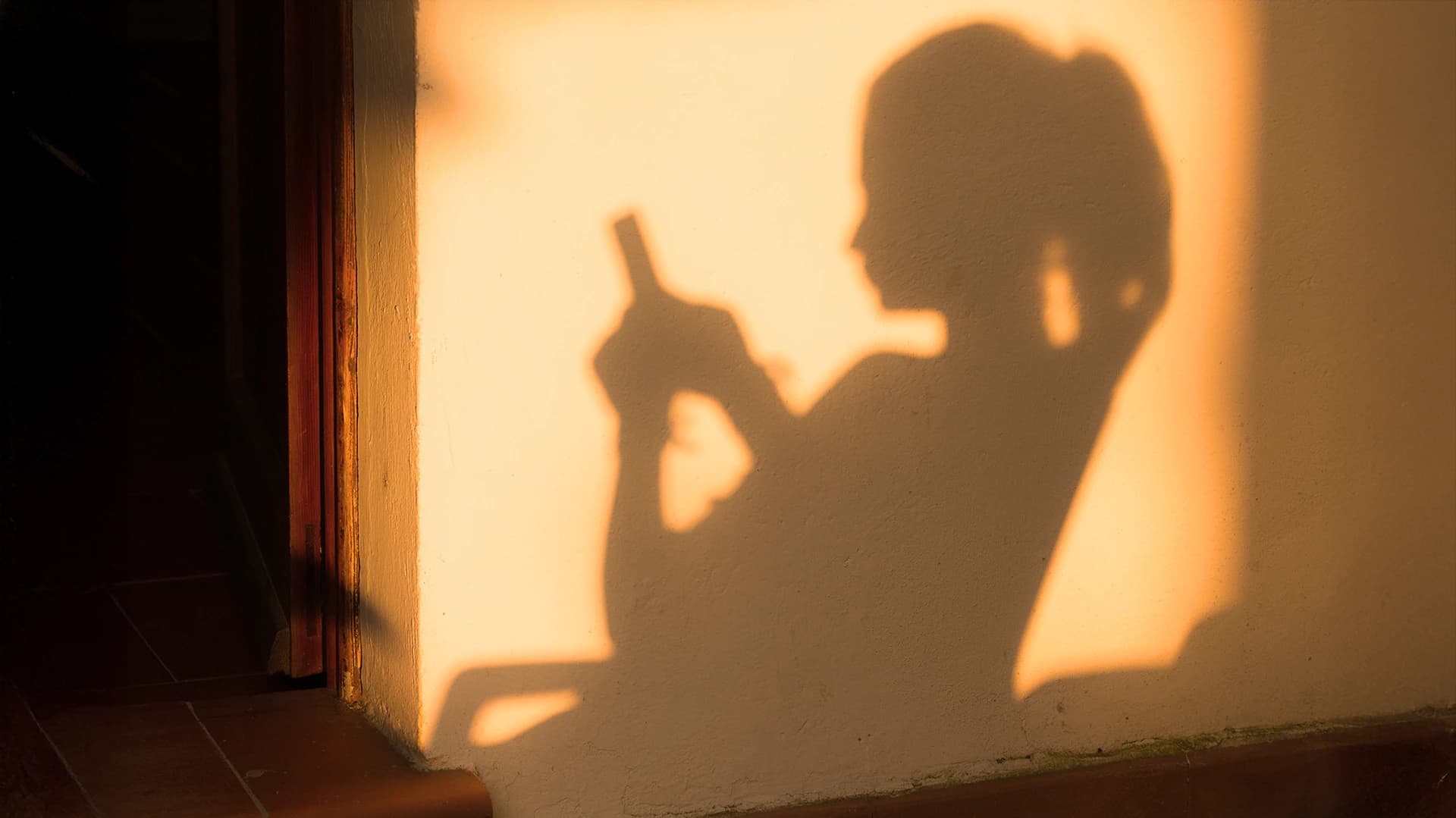 A sillhouette of a woman on a phone