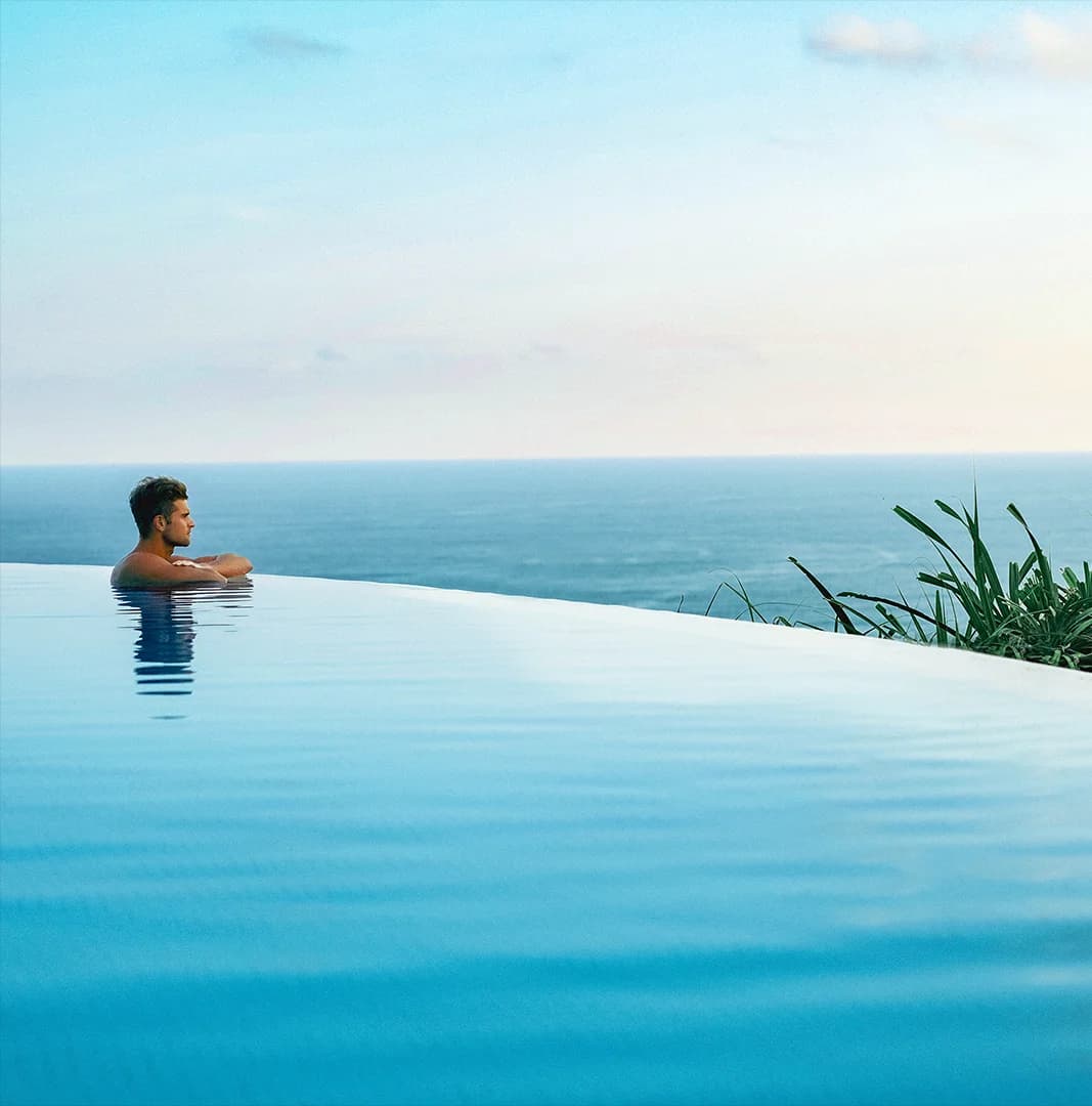 A man sitting in a pool looking over the ocean